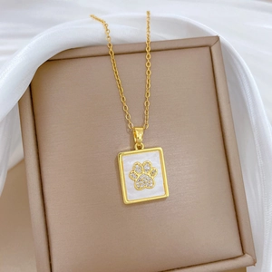 Detailed close-up of golden cat paw necklace with white shell inlay and sparkling crystals