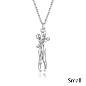 Close-up of small silver hugging couple pendant on a delicate chain necklace