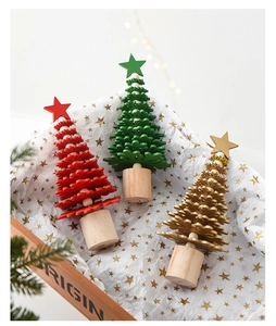 Miniature wooden Christmas trees in red green and gold colors inside a festive gift box