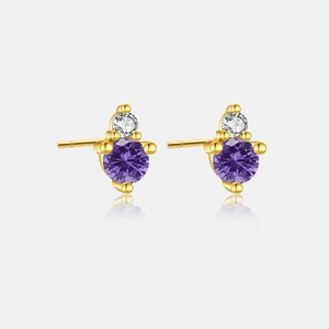 Detail of gold stud earrings featuring a purple gemstone and small diamond stone