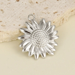 Macro shot of silver sunflower sun pendant charm on stone background for DIY jewelry
