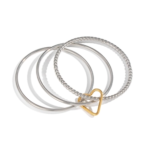 Detail of layered silver circular bracelets with a contrasting gold heart charm connector