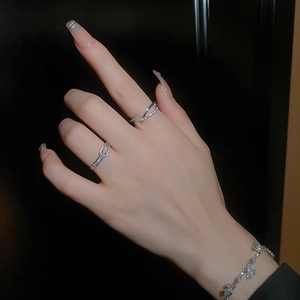 Détail de bagues croisées argentées et d'un bracelet floral serti de zircons