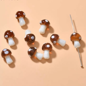 Detailed view of eight handmade mushroom glass beads with brown caps and white spots