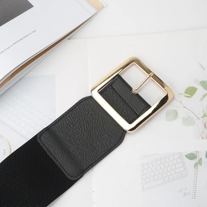 Macro detail of elastic black waist belt with gold square buckle and leather texture