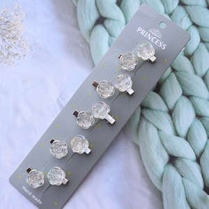 Set of 10 iridescent resin rose hair clips on display card with blue knit texture
