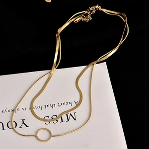 Double layered gold snake bone necklace with round pendant on elegant black background