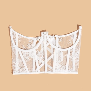 White lace corset top with structured boning and sheer mesh design in flat lay view