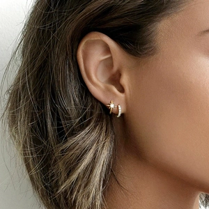Close-up of S925 silver needle star earrings with white stones on a model's ear