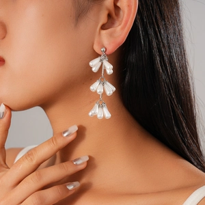 Close-up of elegant silver drop earrings with triple white faux pearl tassels on model