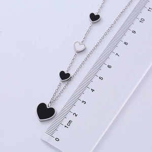 Close-up of stainless steel heart pendant necklace with black and white enamel detail