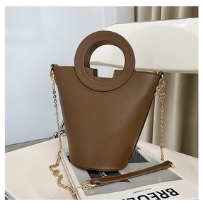Detail of a brown PU leather bucket bag with a round handle and golden chain strap