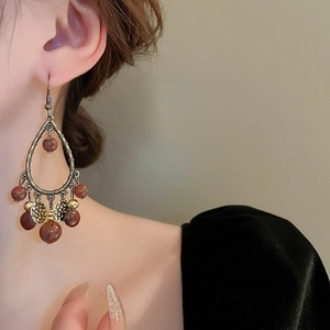 Detail of vintage ethnic teardrop earrings with bronze metal and marbled brown beads