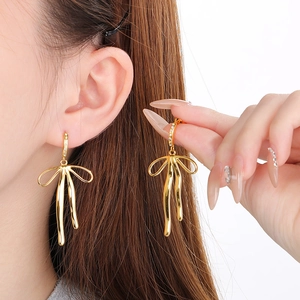 Elegant 18K gold butterfly bow earrings with sparkling cubic zirconia on model
