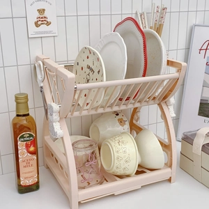 Modern 2-tier pink kitchen dish drying rack with utensil hooks on a tiled background