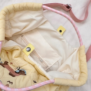 Interior detail of yellow quilted bag with inner zipper pocket and cartoon dog embroidery