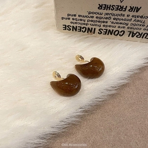 Detail of amber texture resin clip-on earrings with gold metal on white faux fur