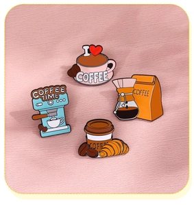 Detail of four coffee enamel pins including a croissant and cup on pink knit background