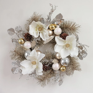 Christmas wreath featuring white magnolia flowers, pine cones, and festive silver ornaments