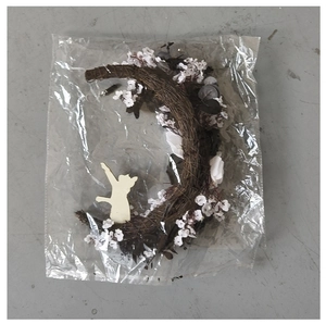 Detail of crescent moon wreath with white flowers and a cat silhouette in plastic packaging