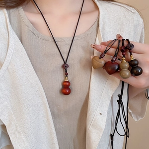 Detail of wooden gourd and heart pendants on black wax rope for ethnic style necklace