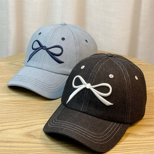 Denim baseball caps with bow embroidery in grey and black on a wooden background