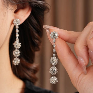 Close-up of sparkling silver floral drop earrings with five layered zircon stones