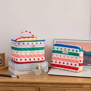Lifestyle shot of quilted cotton makeup bags with stripes and dots on a wooden desk