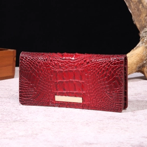 Detail of red crocodile texture wallet with glossy finish and gold metal hardware plaque