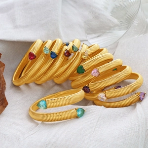 Gold spiral spring bracelet set with colorful heart gemstones on textured linen background