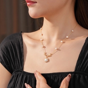 Dettaglio della collana a corna dorate con perla e zircone sul collo di una donna