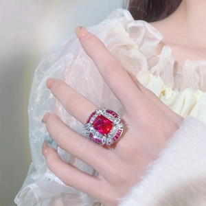 Adjustable silver ring featuring a large square red gemstone with diamond halo on finger