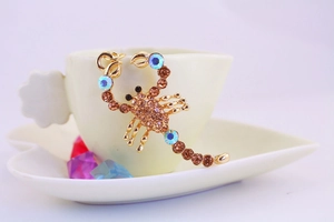 Dettaglio del portachiavi a scorpione con strass ambra e cristalli blu su metallo dorato
