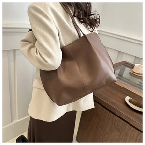 Detailed side view of the large dark brown tote bag with premium leather texture and stitching