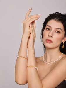 Gros plan sur un bracelet doré élégant avec perles d'eau douce au poignet féminin