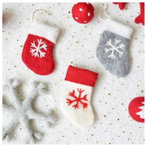 Detail of handmade wool felt Christmas stockings and snowflake ornaments on starry background