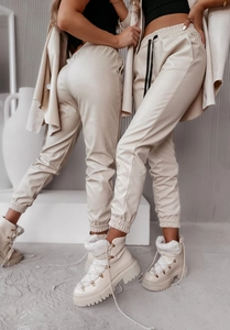 Dettaglio dei pantaloni jogger in ecopelle beige opaco con vita alta elastica e polsini