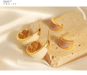 Detail of C-shaped enamel earrings in cream and dusty pink with gold accents