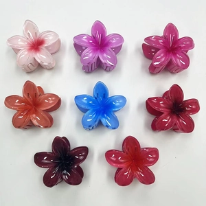Flat lay of eight colorful gradient frangipani flower hair claws on a white background