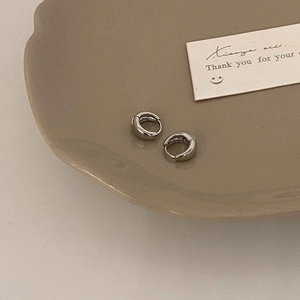 Detailed view of silver hoop earrings on a ceramic tray with a minimalist design