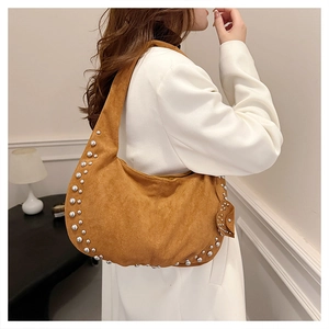 Sac croissant en daim marron avec détails de rivets argentés porté par un mannequin