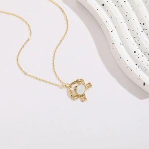 Detail shot of crab pendant necklace with shell inlay and gold-plated chain