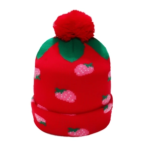 Close-up of a red knit strawberry hat featuring a green leaf top and fluffy pom-pom