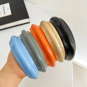 Close-up of five textured leather sponge headbands in blue, grey, orange, gold, and black