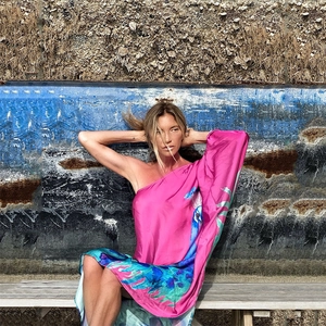 Detail eines Maxikleides mit Seidentextur, Pfauenprint und asymmetrischem One-Shoulder-Design