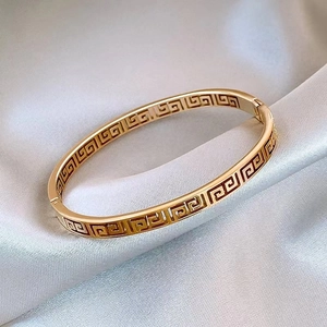 Macro shot of gold Greca pattern hollow engraving on a stainless steel bangle