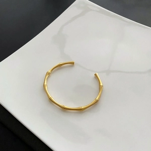 Detail shot of golden bamboo texture cuff bracelet on elegant ceramic display tray