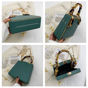 Detail view of dark green leather square handbag with floral scarf and gold chain strap