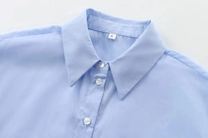 Détail du col d'une chemise en coton bleu clair avec étiquette de taille S