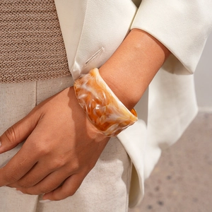 Close-up of amber marble textured resin bangle on wrist with elegant minimalist aesthetics